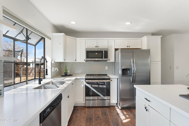 kitchen featuring light countertops, a sink, stainless steel appliances, and tasteful backsplash