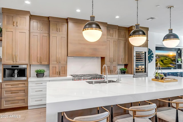 kitchen with a breakfast bar, sink, beverage cooler, stainless steel appliances, and a large island