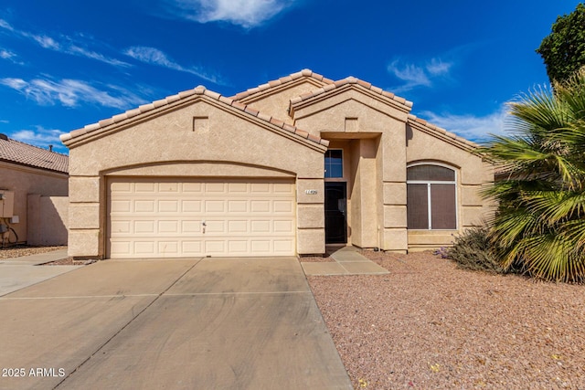 mediterranean / spanish-style house featuring a garage, concrete driveway, a tiled roof, and stucco siding