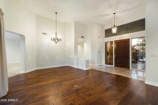 empty room featuring a towering ceiling and dark hardwood / wood-style floors