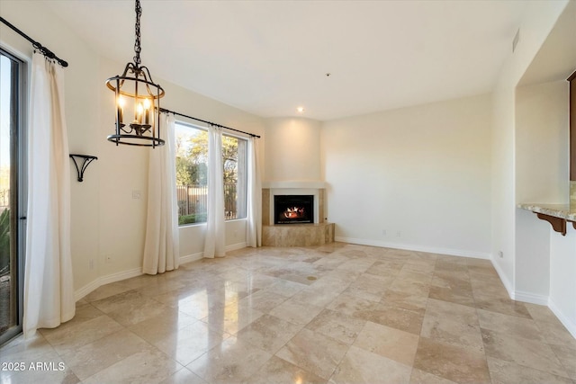 unfurnished living room with a chandelier and a fireplace