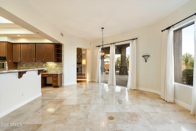 kitchen with plenty of natural light, hanging light fixtures, a kitchen breakfast bar, and oven