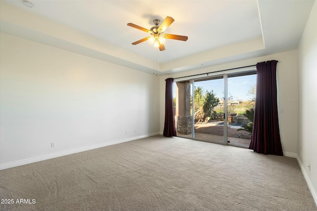 carpeted empty room with ceiling fan and a tray ceiling