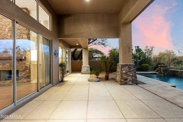 patio terrace at dusk with pool water feature and a fenced in pool