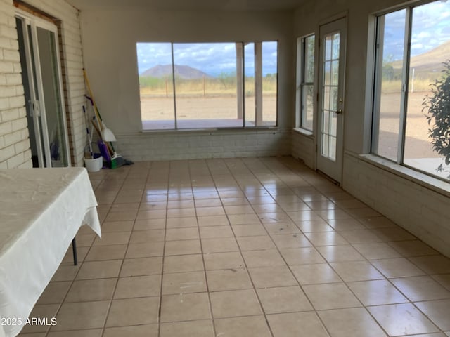 3607 E Mule Deer Rd, Pearce, AZ 85625 - unfurnished sunroom featuring a mountain view, tile patterned flooring, and brick wall