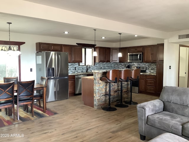 3607 E Mule Deer Rd, Pearce, AZ 85625 - kitchen featuring stainless steel appliances, open floor plan, tasteful backsplash, light wood-type flooring, and dark brown cabinets