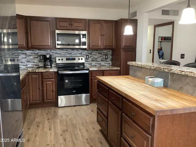 3607 E Mule Deer Rd, Pearce, AZ 85625 - kitchen with appliances with stainless steel finishes, butcher block countertops, light wood-style floors, and decorative backsplash
