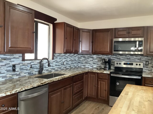 3607 E Mule Deer Rd, Pearce, AZ 85625 - kitchen with stainless steel appliances, a sink, butcher block countertops, light wood finished floors, and decorative backsplash