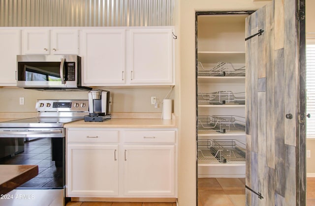 kitchen featuring a wealth of natural light, light countertops, appliances with stainless steel finishes, and white cabinetry