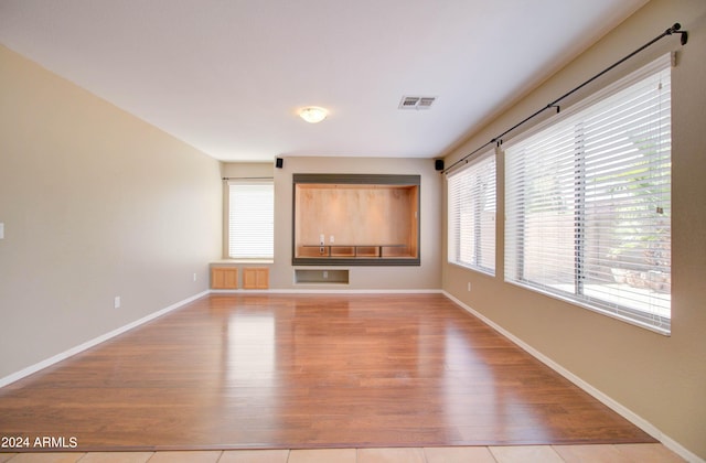 unfurnished living room with light wood finished floors, baseboards, and visible vents