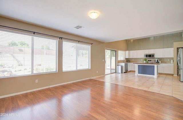 unfurnished living room with visible vents, light wood-style flooring, and baseboards