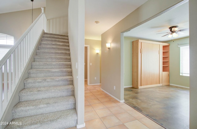 stairway with a ceiling fan, tile patterned flooring, and baseboards