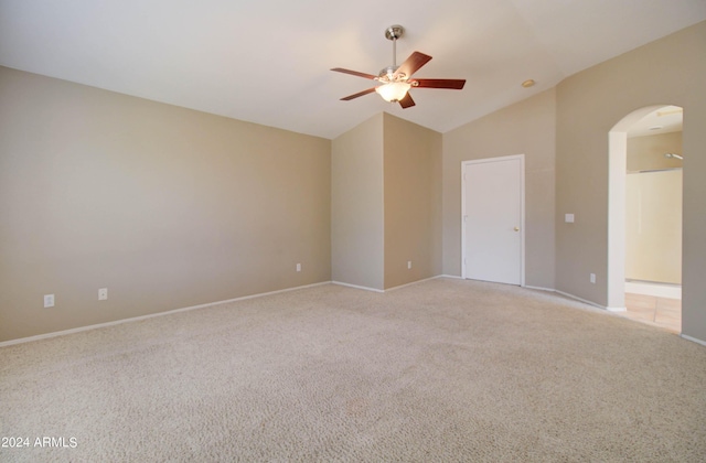 unfurnished room with light carpet, arched walkways, vaulted ceiling, and a ceiling fan