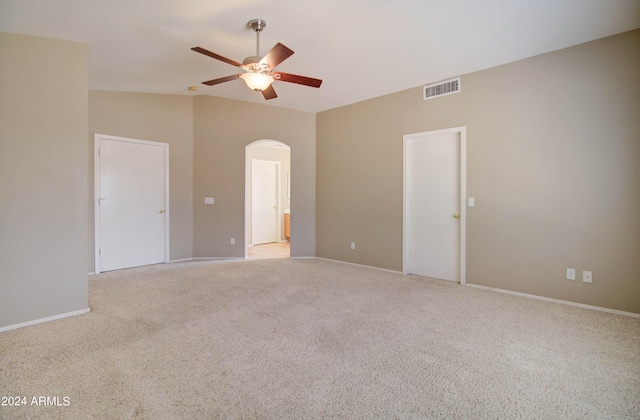 unfurnished bedroom with arched walkways, lofted ceiling, light colored carpet, a ceiling fan, and visible vents