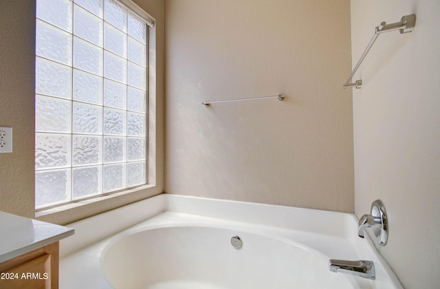 full bathroom featuring a healthy amount of sunlight, a bath, and vanity