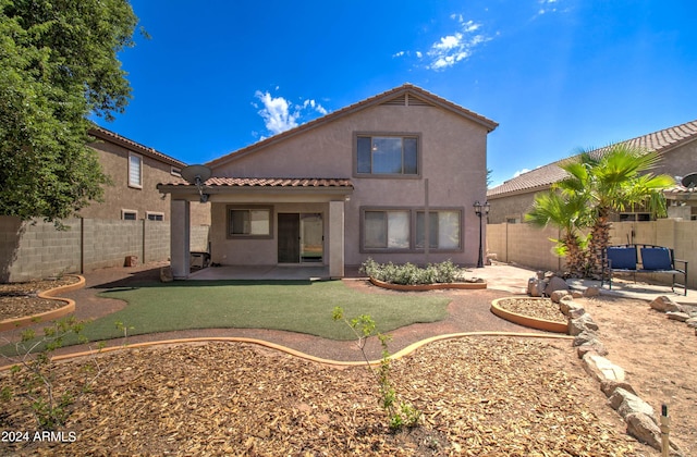 rear view of property with a tiled roof, a patio area, a fenced backyard, and stucco siding