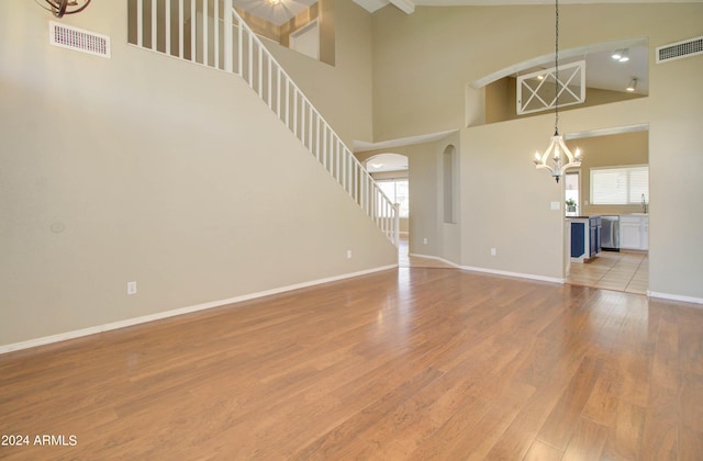 unfurnished living room with a chandelier, a wealth of natural light, visible vents, and light wood-style flooring