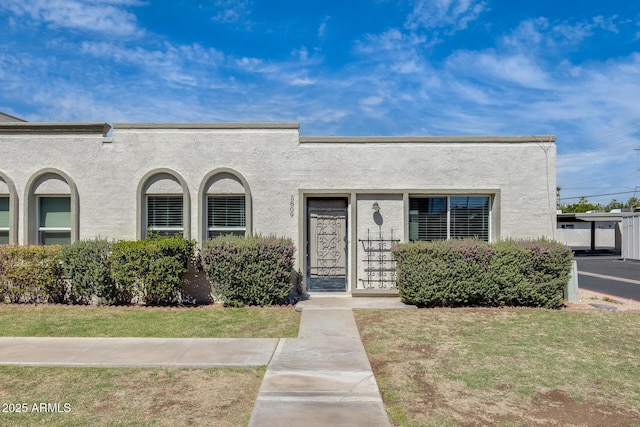 view of front facade featuring stucco siding and a front yard