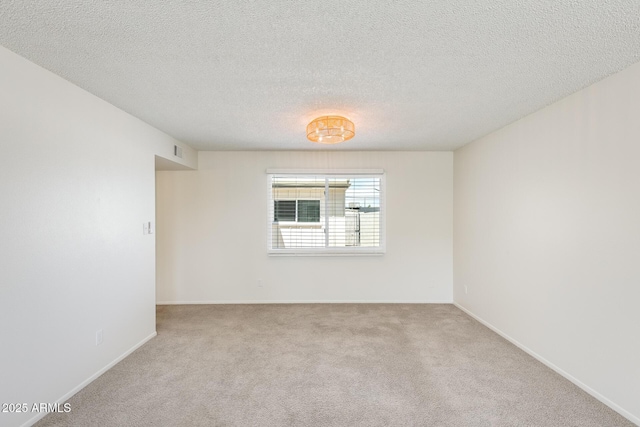 unfurnished room with carpet flooring, a textured ceiling, and baseboards