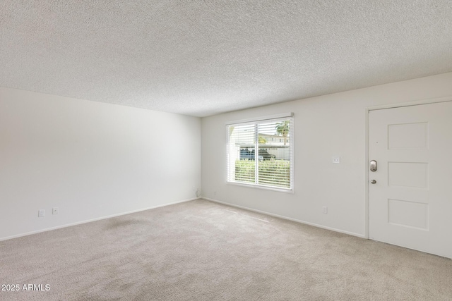 empty room featuring carpet flooring, a textured ceiling, and baseboards