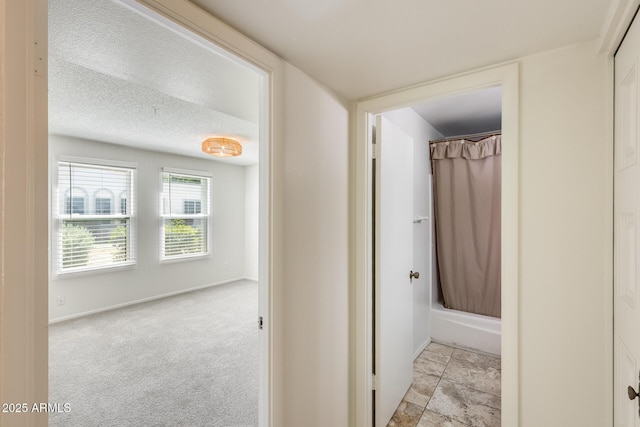 hall featuring baseboards and a textured ceiling