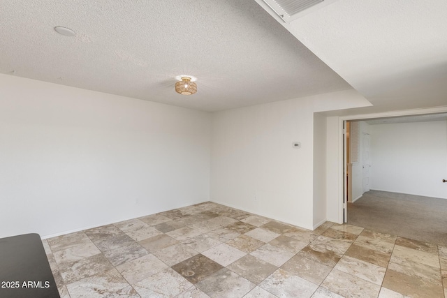 spare room with light stone finish floors and a textured ceiling