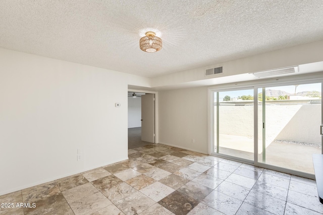 unfurnished room with baseboards, stone tile flooring, and a textured ceiling
