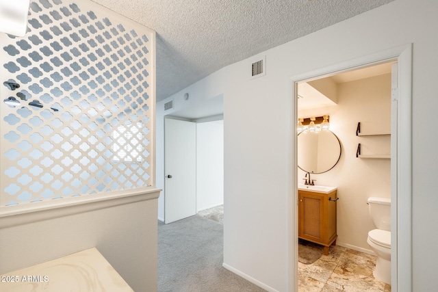 bathroom featuring toilet, vanity, a textured ceiling, and baseboards
