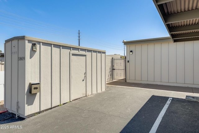view of shed featuring a gate, uncovered parking, and fence