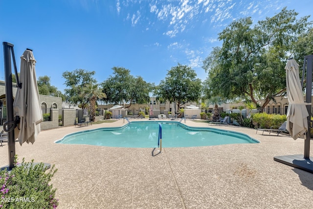 community pool with a patio and fence