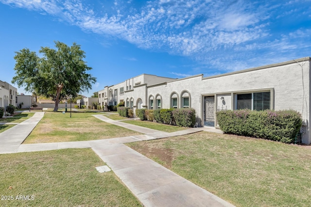 view of front of property with stucco siding, a front lawn, and a residential view