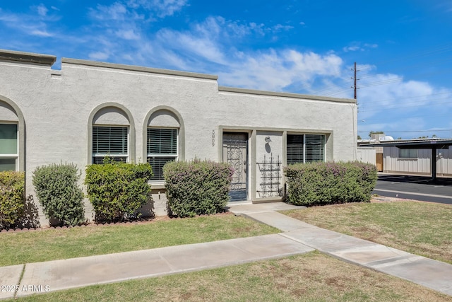 view of front of home featuring stucco siding and a front yard