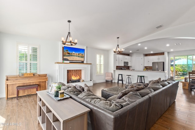 living room featuring wood-type flooring, a fireplace, and an inviting chandelier