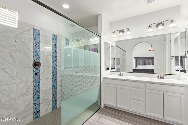 bathroom with tiled shower, tile patterned flooring, and vanity