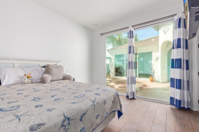 bedroom with lofted ceiling, hardwood / wood-style flooring, and access to outside