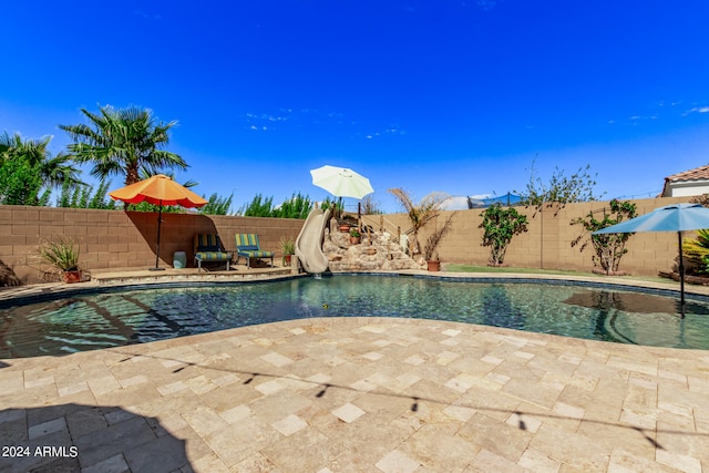 view of swimming pool featuring a water slide and a patio