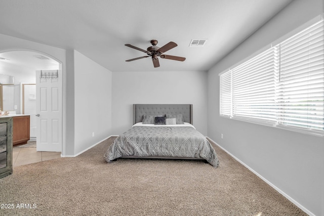 14521 W Gelding Dr, Surprise, AZ 85379 - bedroom with light colored carpet, baseboards, arched walkways, ensuite bath, and visible vents