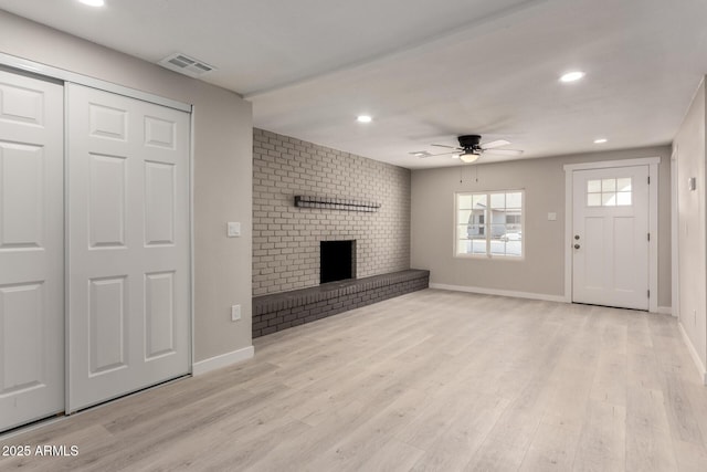 unfurnished living room featuring ceiling fan, light hardwood / wood-style floors, and a brick fireplace