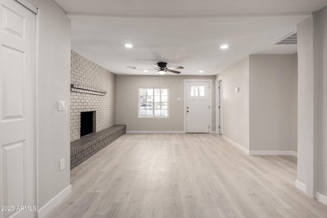 unfurnished living room featuring ceiling fan, a brick fireplace, and light hardwood / wood-style flooring