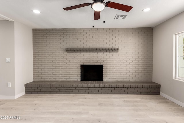 unfurnished living room with brick wall, a healthy amount of sunlight, and light hardwood / wood-style floors