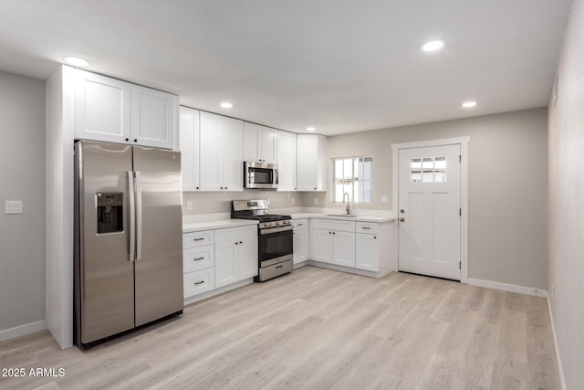 kitchen featuring light wood-type flooring, stainless steel appliances, sink, and white cabinets