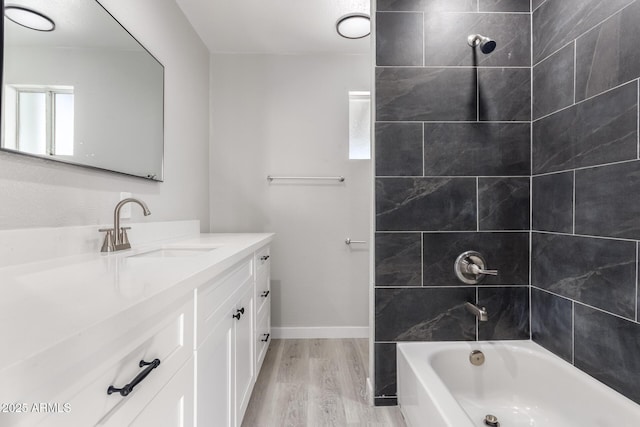 bathroom with hardwood / wood-style flooring, tiled shower / bath, and vanity