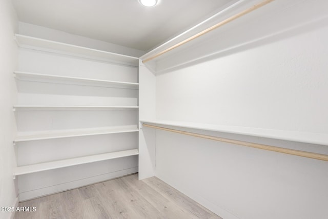 walk in closet with light hardwood / wood-style floors