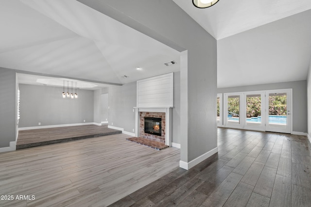 3822 E Florian Ave, Mesa, AZ 85206 - unfurnished living room featuring high vaulted ceiling, baseboards, wood finished floors, a fireplace, and a chandelier