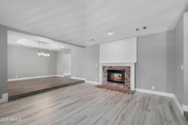 3822 E Florian Ave, Mesa, AZ 85206 - unfurnished living room featuring wood finished floors, baseboards, a brick fireplace, and a chandelier