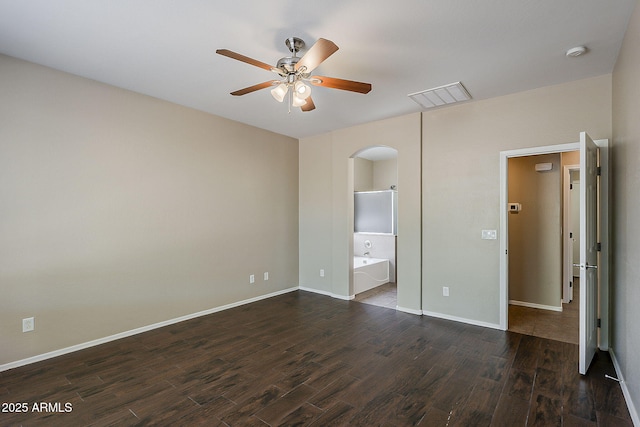 5926 W Questa Dr, Glendale, AZ 85310 - unfurnished bedroom with dark wood-style flooring, visible vents, arched walkways, baseboards, and ensuite bathroom