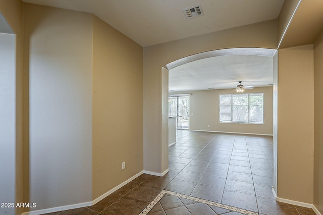 5926 W Questa Dr, Glendale, AZ 85310 - tiled empty room featuring arched walkways, baseboards, a ceiling fan, and visible vents