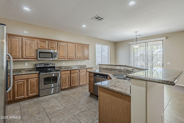 5926 W Questa Dr, Glendale, AZ 85310 - kitchen with a kitchen island with sink, visible vents, brown cabinets, a sink, and stainless steel appliances