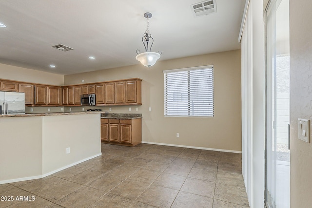5926 W Questa Dr, Glendale, AZ 85310 - kitchen with visible vents, pendant lighting, brown cabinetry, and appliances with stainless steel finishes