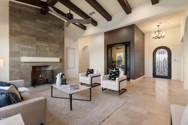 8599 E Sand Flower Dr, Scottsdale, AZ 85266 - living room featuring a tile fireplace, arched walkways, beam ceiling, high vaulted ceiling, and ceiling fan with notable chandelier